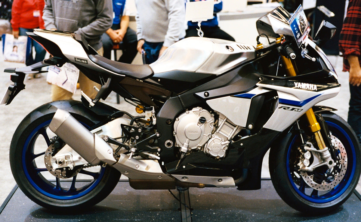 Real 2015 Yamaha YZF-R1M motorcycle in silver black and blue at a motorcycle show, full side view; R1M variant, editorial photograph by Dennis Bratland CC BY-SA 4.0