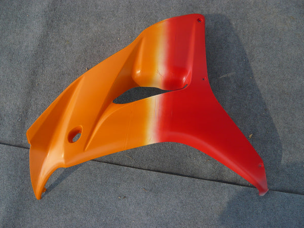 Orange-red motorcycle fairing panel at the NiceFairings workshop during paint preparation