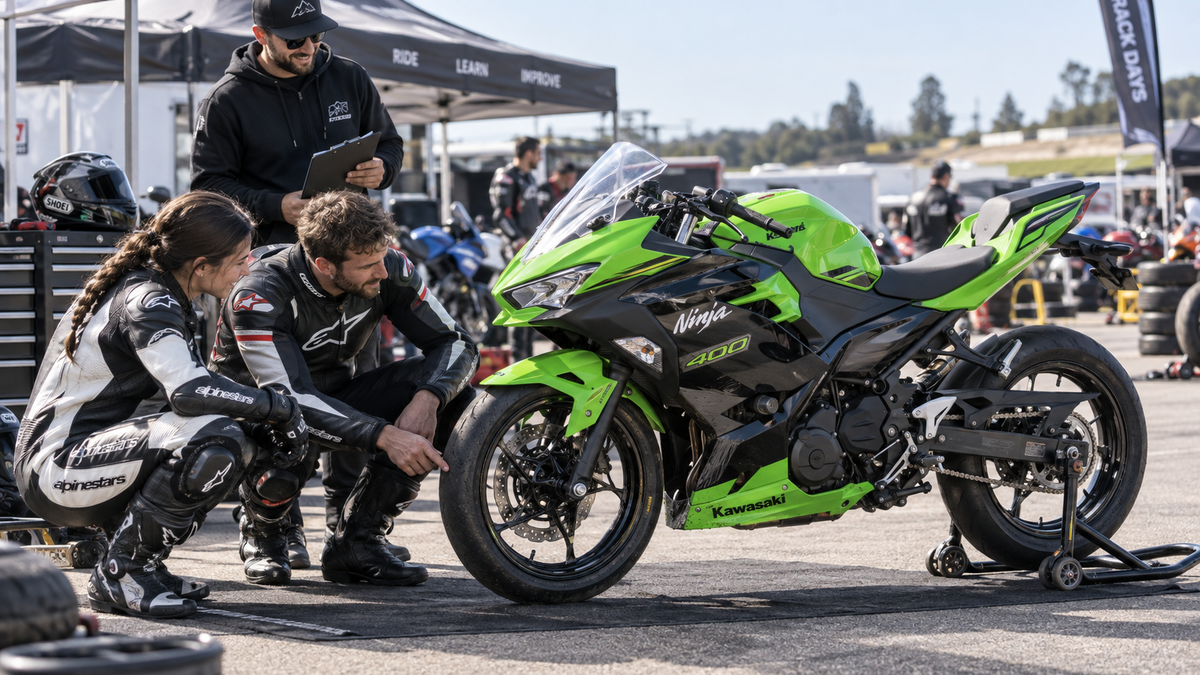 Kawasaki Ninja 400 2018–2023 style motorcycle being inspected by riders in a sunny club track paddock