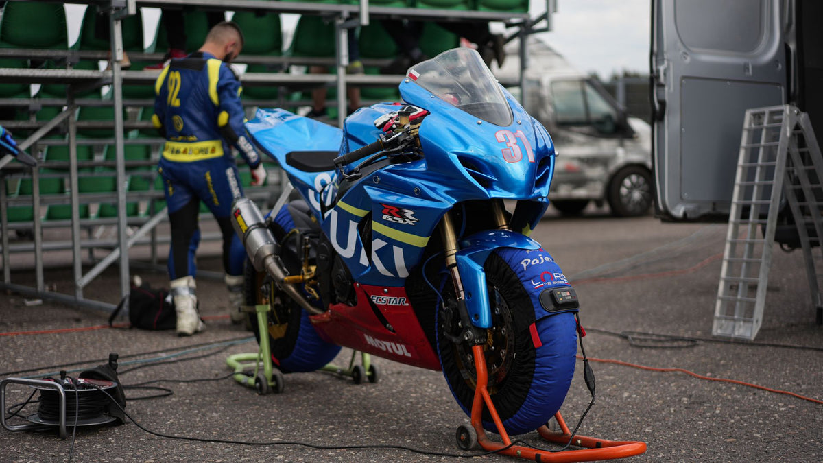 Fully faired Suzuki sport motorcycle being prepared in a race paddock before installation checks