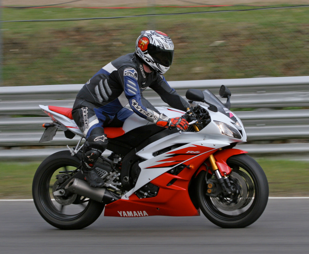 Real red and white Yamaha R6 being ridden; contextual image of a fully faired sportbike, not a verified frame-slider installation