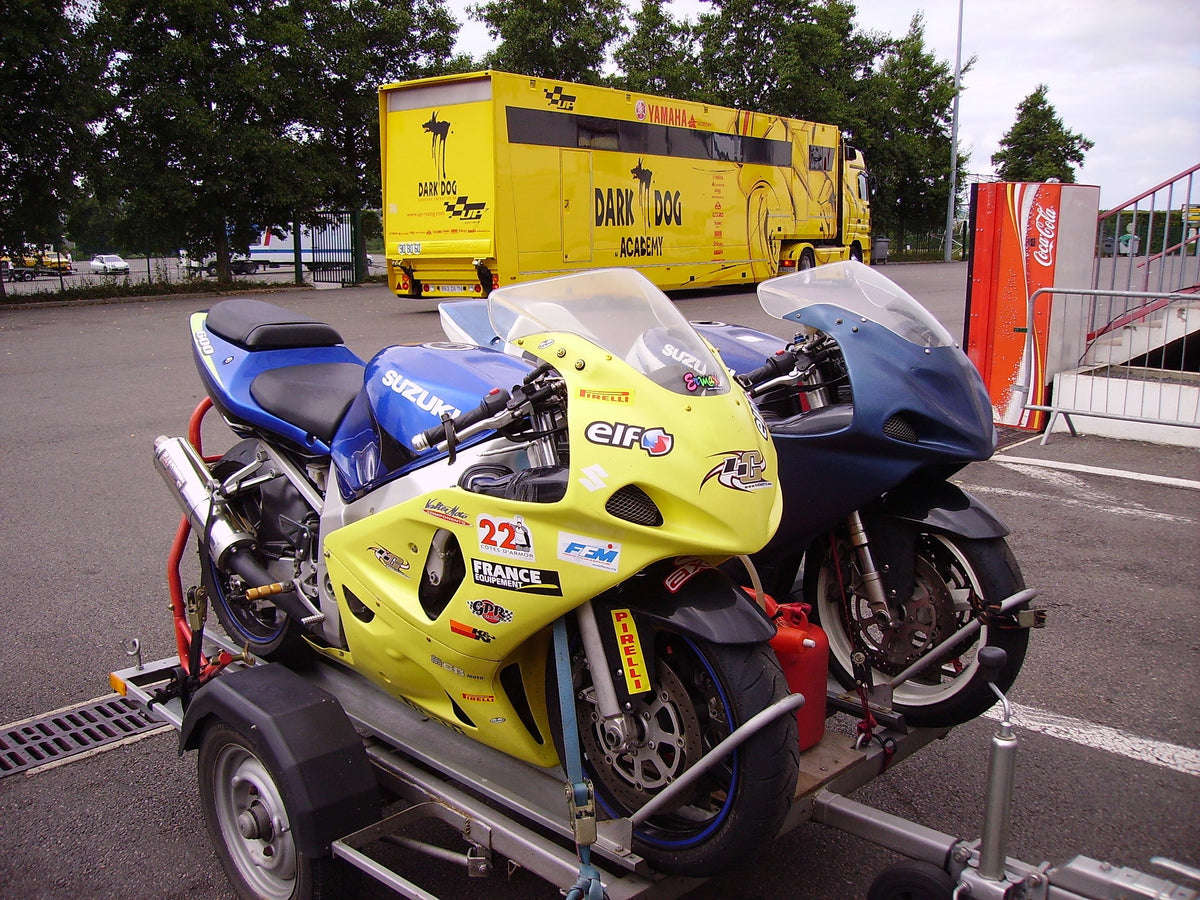 Two Suzuki GSX-R sportbikes sharing a small trailer at Magny-Cours, France; real 2009 editorial photograph, not a NiceFairings product.