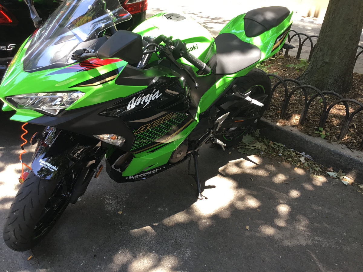 Real green Kawasaki Ninja 400 parked on a city street, with its road headlight, indicator and mirror visible; reference photo, not crash evidence