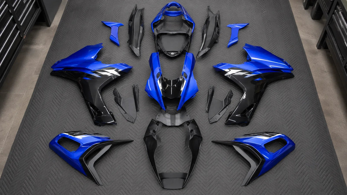 Blue and black complete motorcycle fairing panel set arranged on a workshop floor