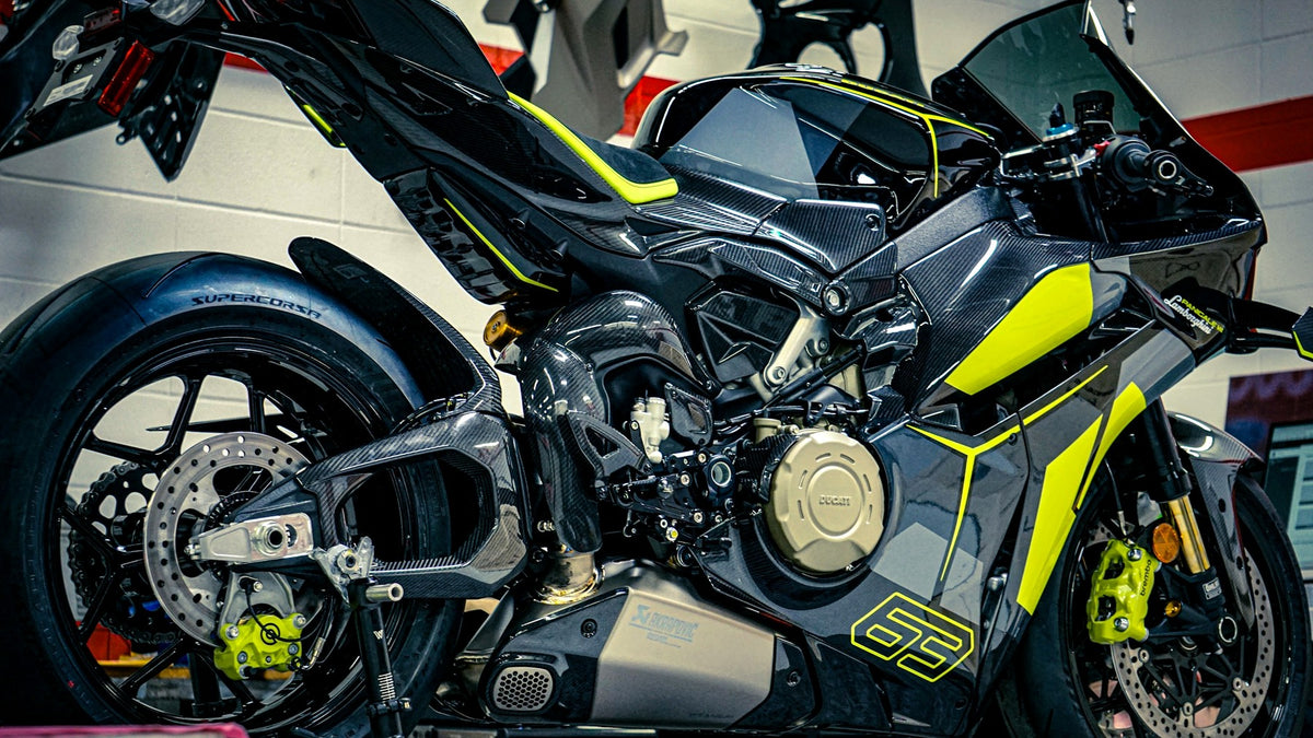 Fully faired black and yellow sportbike in a workshop with the lower fairing and exhaust heat zone clearly visible