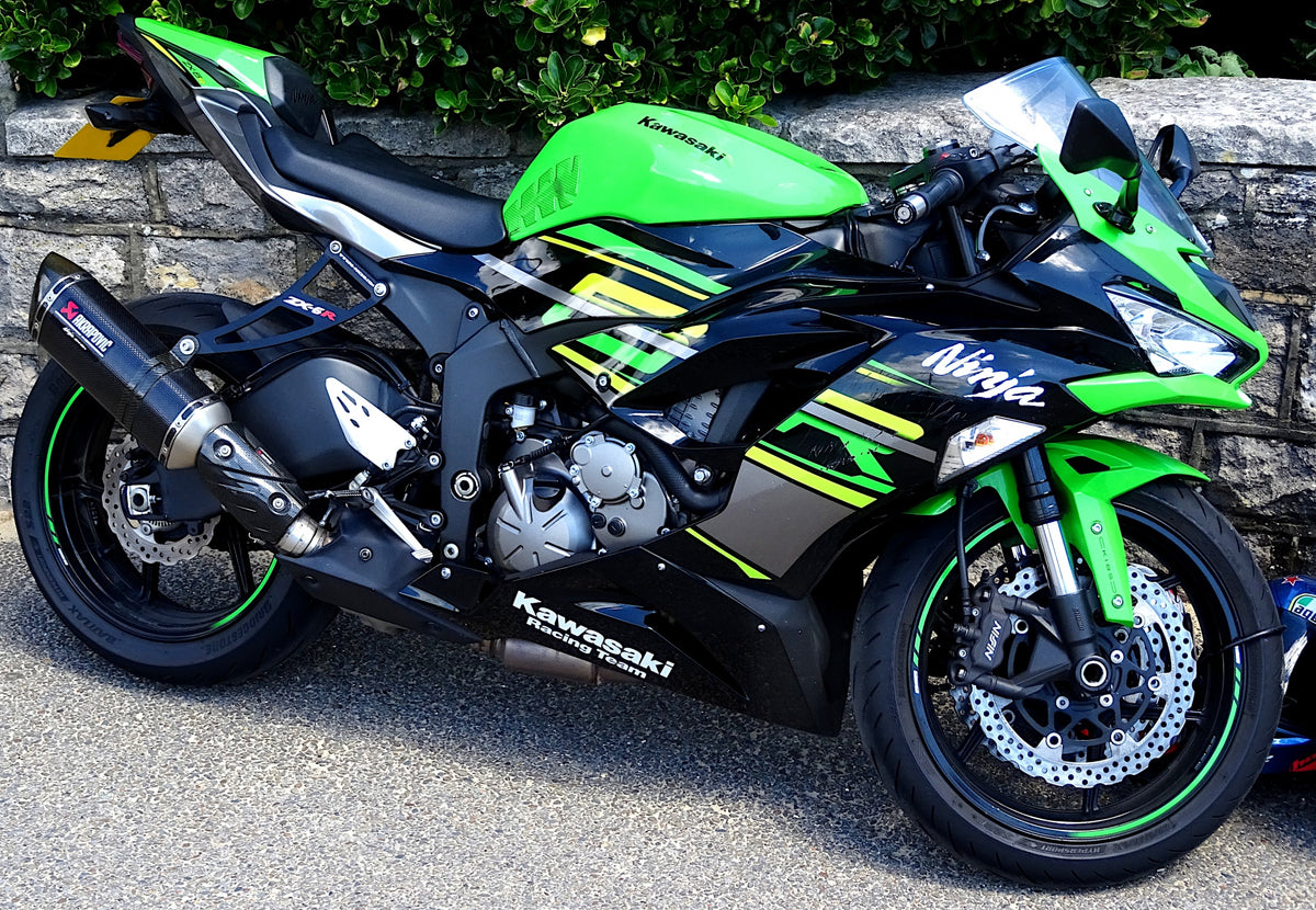 Real green-and-black Kawasaki Ninja ZX-6R parked beside a stone wall; Sound Media CC0 editorial photo, not the hypothetical motorcycle or a NiceFairings installation