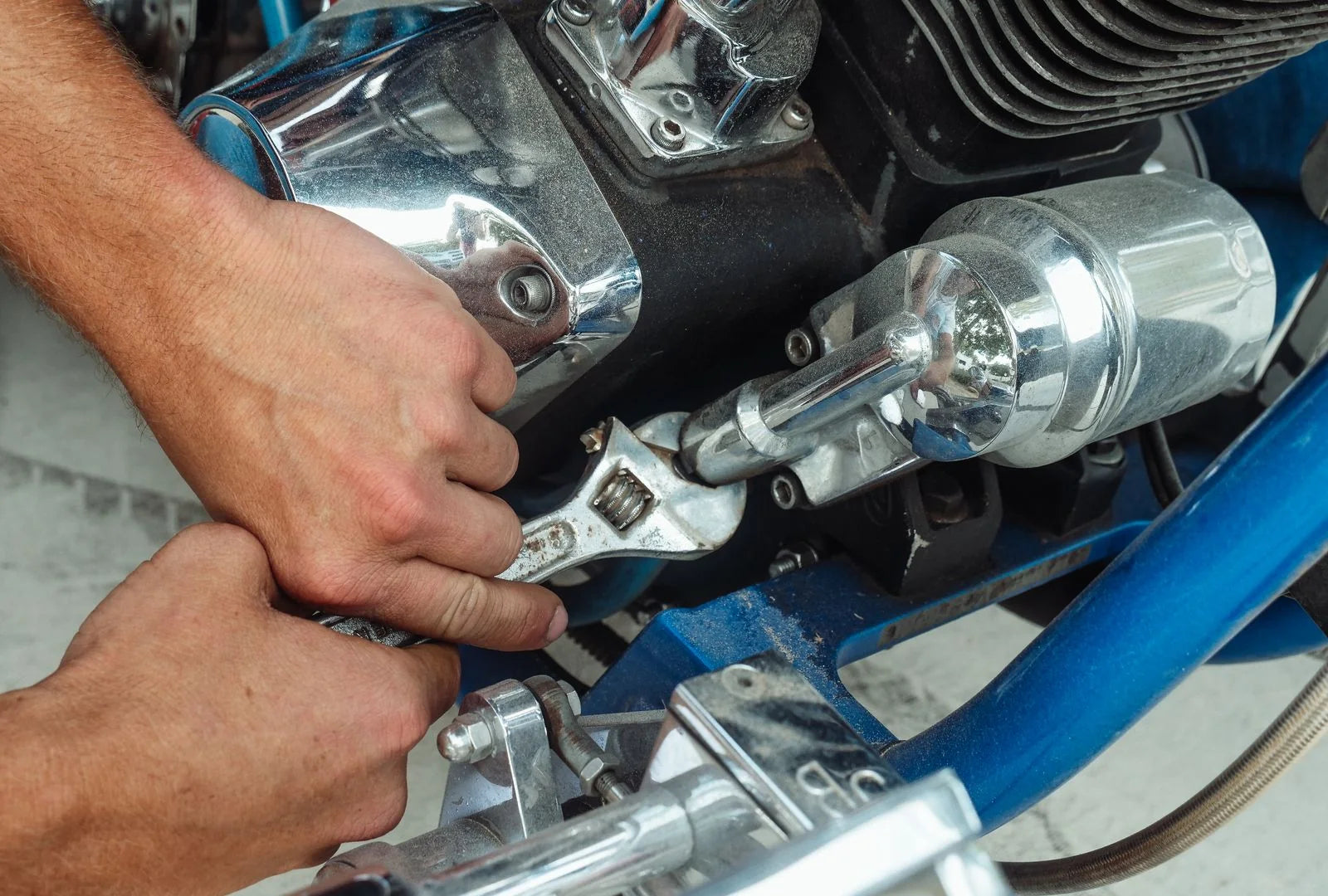 Close-up of hands performing motorcycle maintenance with a wrench